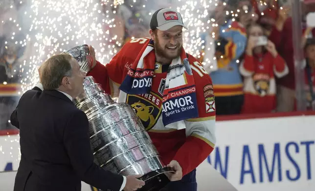 NHL commissioner Gary Bettman, left, presents the Stanley Cup to Florida Panthers center Aleksander Barkov after the Panthers beat the Edmonton Oilers in Game 7 of the NHL hockey Stanley Cup Finals, Monday, June 24, 2024, in Sunrise, Fla. (AP Photo/Wilfredo Lee)