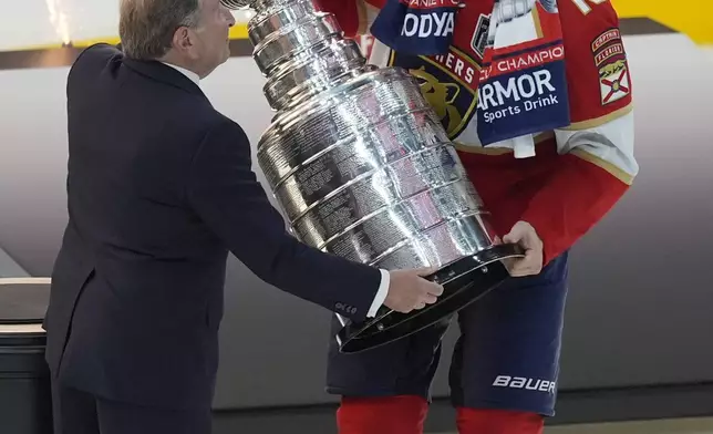 Florida Panthers center Aleksander Barkov (16) receives the Stanley Cup trophy from NHL commissioner Gary Bettman after Game 7 of the NHL hockey Stanley Cup Final, Monday, June 24, 2024, in Sunrise, Fla. The Panthers defeated the Oilers 2-1 to win the Stanley Cup. (AP Photo/Rebecca Blackwell)