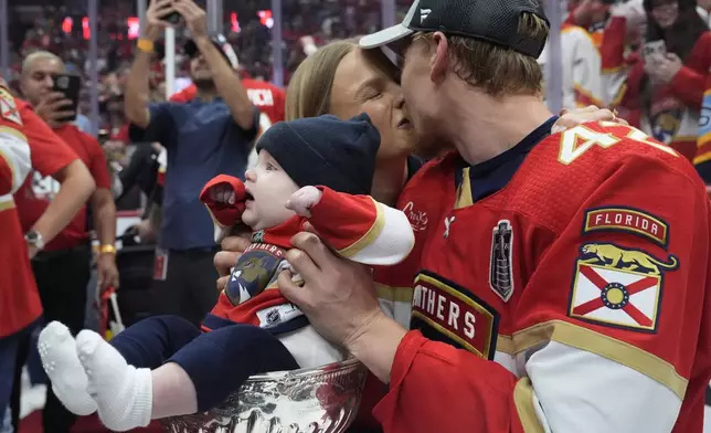 Florida Panthers defenseman Gustav Forsling kisses his wife Daniela as he places his five-month-old son Bo on the Stanley Cup trophy, Tuesday, June 25, 2024, in Sunrise, Fla. The Panthers defeated the Oilers 2-1 to win the Stanley Cup. (AP Photo/Wilfredo Lee)