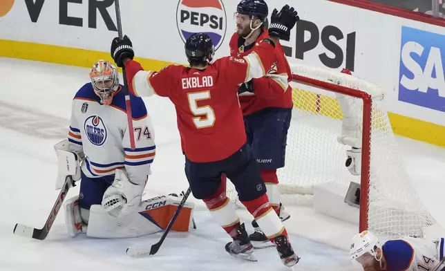 Florida Panthers defenseman Aaron Ekblad (5) congratulates left wing Matthew Tkachuk (19) after Tkachuk scored a goal against Edmonton Oilers goaltender Stuart Skinner (74) during the second period of Game 5 of the NHL hockey Stanley Cup Finals, Tuesday, June 18, 2024, in Sunrise, Fla. (AP Photo/Rebecca Blackwell)