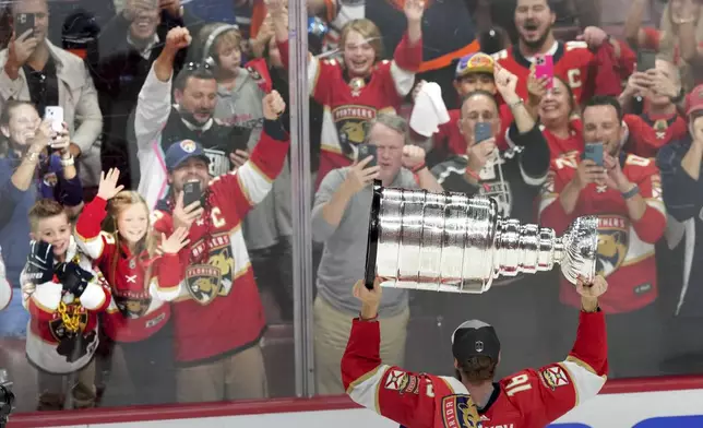 Florida Panthers forward Aleksander Barkov (16) hoists the NHL hockey Stanley Cup in front of fans after defeating the Edmonton Oilers in Sunrise, Fla., Monday, June 24, 2024. (Nathan Denette/The Canadian Press via AP)