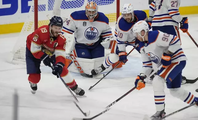 Edmonton Oilers right wing Corey Perry (90) moves the puck away from Florida Panthers left wing Matthew Tkachuk (19) during the first period of Game 5 of the NHL hockey Stanley Cup Finals, Tuesday, June 18, 2024, in Sunrise, Fla. (AP Photo/Rebecca Blackwell)