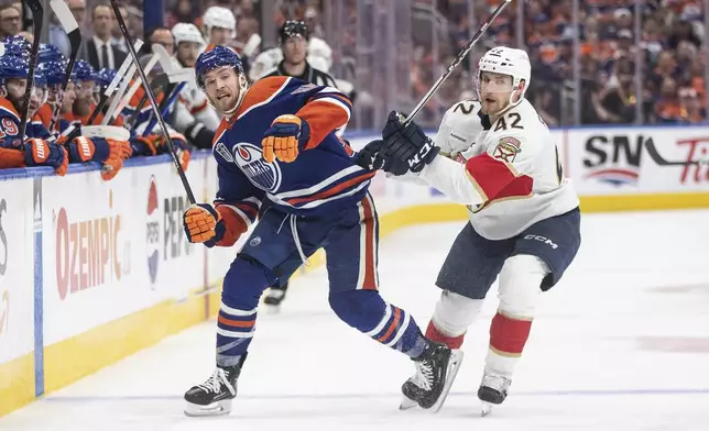 Florida Panthers' Gustav Forsling (42) checks Edmonton Oilers' Dylan Holloway (55) during the second period of Game 6 of the NHL hockey Stanley Cup Final, Friday, June 21, 2024, in Edmonton, Alberta. (Jason Franson/The Canadian Press via AP)