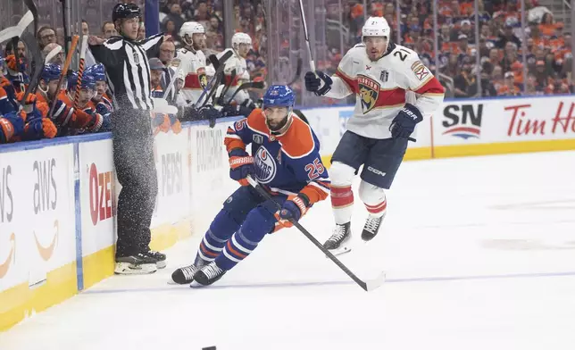 Florida Panthers' Nick Cousins (21) dodges a hit from Edmonton Oilers' Darnell Nurse (25) during the first period of Game 6 of the NHL hockey Stanley Cup Final, Friday, June 21, 2024, in Edmonton, Alberta. (Jason Franson/The Canadian Press via AP)