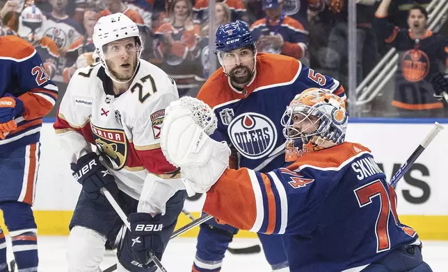 Florida Panthers' Eetu Luostarinen (27) and Edmonton Oilers' Cody Ceci (5) look for the rebound on a save by goalie Stuart Skinner (74) during the third period of Game 6 of the NHL hockey Stanley Cup Final, Friday, June 21, 2024, in Edmonton, Alberta. The Oilers won 5-1 to tie the series. (Jason Franson/The Canadian Press via AP)