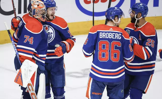 Edmonton Oilers goalie Stuart Skinner (74) celebrates his assist with Mattias Janmark (13) Philip Broberg (86) and Darnell Nurse (25) on an empty-net goal against the Florida Panthers during the third period of Game 6 of the NHL hockey Stanley Cup Final, Friday, June 21, 2024, in Edmonton, Alberta. The Oilers won 5-1 to tie the series. (Jeff McIntosh/The Canadian Press via AP)