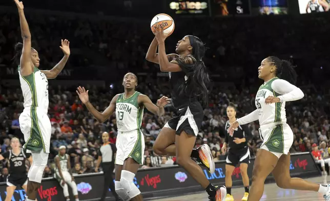 Las Vegas Aces guard Jackie Young (0) shoots a layup against Seattle Storm guard Jewell Loyd, left, center Ezi Magbegor (13) and guard Victoria Vivians (35) during the first half of an WNBA basketball game Wednesday, June 19, 2024, in Las Vegas. (Steve Marcus/Las Vegas Sun via AP)