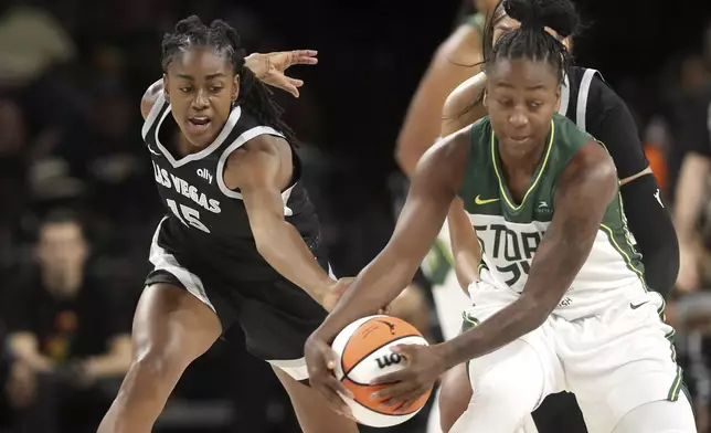 Las Vegas Aces guard Tiffany Hayes (15) and Seattle Storm guard Jewell Loyd (24) fight for the ball during the first half of an WNBA basketball game Wednesday, June 19, 2024, in Las Vegas. (Steve Marcus/Las Vegas Sun via AP)