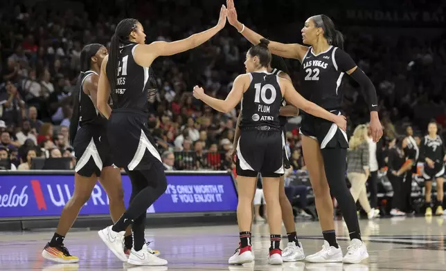 Las Vegas Aces center A'ja Wilson (22) is congratulated by teammates Kiah Stokes (41) and Kelsey Plum (10) after scoring a basket and drawing a foul during the first half of an WNBA basketball game against the Seattle Storm Wednesday, June 19, 2024, in Las Vegas. (Steve Marcus/Las Vegas Sun via AP)