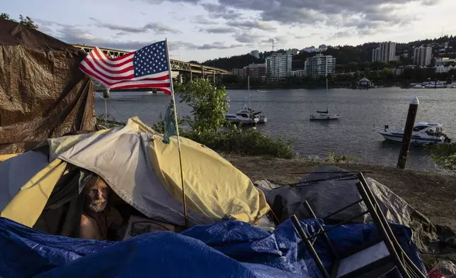 FILE - Frank, a homeless man, sits in his tent with a river view, June 5, 2021, in Portland, Ore. The Supreme Court ruled on Friday, June 28, 2024, that cities can enforce bans on homeless people sleeping outdoors in West Coast areas where shelter space is lacking. (AP Photo/Paula Bronstein, File)