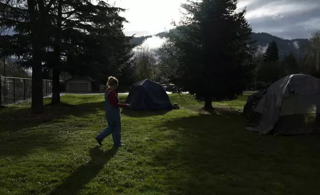 FILE - Cassy Leach, a nurse who leads a group of volunteers who provide food, medical care and other basic goods to the hundreds of homeless people living in the parks, walks to help homeless people camping in Fruitdale Park move their tents, March 23, 2024, in Grants Pass, Ore. On Friday, June 28, the Supreme Court ruled that cities can enforce bans on homeless people sleeping outdoors in West Coast areas where shelter space is lacking. (AP Photo/Jenny Kane, File)