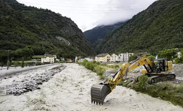 An excavator removes stones from the bed of the Navizence river, which flows into the Rhone, in Chippis, canton Valais, Switzerland, Saturday June 22, 2024. (Jean-Christophe Bott/Keystone via AP)