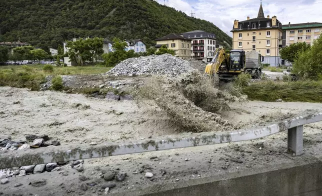 An excavator removes stones from the bed of the Navizence river, which flows into the Rhone, in Chippis, canton Valais, Switzerland, Saturday June 22, 2024. (Jean-Christophe Bott/Keystone via AP)