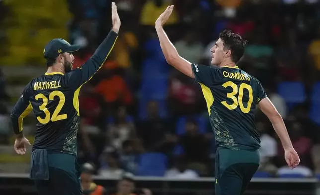 Australia's Pat Cummins, right, is congratulated by teammate Glenn Maxwell after taking the wicket of Bangladesh's Mahmudullah during the ICC Men's T20 World Cup cricket match between Australia and Bangladesh in North Sound, Antigua and Barbuda, Thursday, June 20, 2024. (AP Photo/Lynne Sladky)