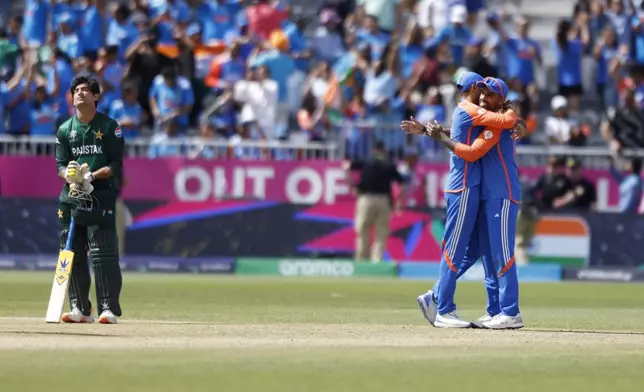 Pakistan's Naseem Shah, left, reacts as Indian players celebrate their win in the ICC Men's T20 World Cup cricket match between India and Pakistan at the Nassau County International Cricket Stadium in Westbury, New York, Sunday, June 9, 2024. (AP Photo/Eduardo Munoz)