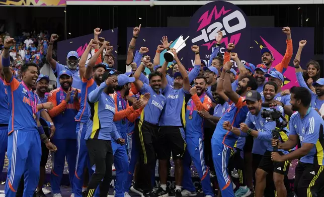 India's head coach Rahul Dravid, center, and players celebrate with the winners trophy after defeating South Africa in the ICC Men's T20 World Cup final cricket match at Kensington Oval in Bridgetown, Barbados, Saturday, June 29, 2024. (AP Photo/Ricardo Mazalan)