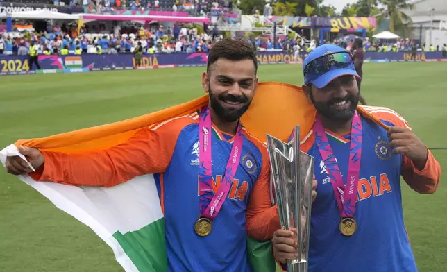 India's Virat Kohli, left, and captain Rohit Sharma pose with the winners trophy after defeating South Africa in the ICC Men's T20 World Cup final cricket match at Kensington Oval in Bridgetown, Barbados, Saturday, June 29, 2024. (AP Photo/Ricardo Mazalan)