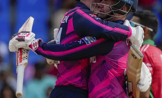 Scotland batsmen Matthew Cross, right, and Brandon McMullen hug after beating Oman during an ICC Men's T20 World Cup cricket match at Sir Vivian Richards Stadium in North Sound, Antigua and Barbuda, Sunday, June 9, 2024. Scotland won by seven wickets with 41 balls remaining. (AP Photo/Ricardo Mazalan)