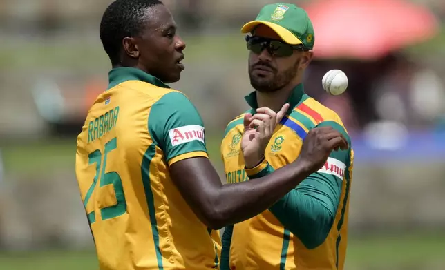 South Africa's Kagiso Rabada, left, listens to captain Aiden Markram before bowling his next delivery during the ICC Men's T20 World Cup cricket match between the United States and South Africa at Sir Vivian Richards Stadium in North Sound, Antigua and Barbuda, Wednesday, June 19, 2024. (AP Photo/Ricardo Mazalan)