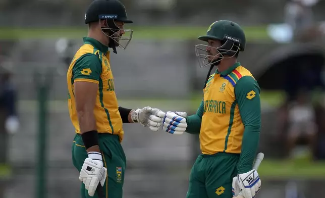 South Africa's captain Aiden Markram, left, fist bumps with batting partner Quinton de Kock during the ICC Men's T20 World Cup cricket match between the United States and South Africa at Sir Vivian Richards Stadium in North Sound, Antigua and Barbuda, Wednesday, June 19, 2024. (AP Photo/Ricardo Mazalan)