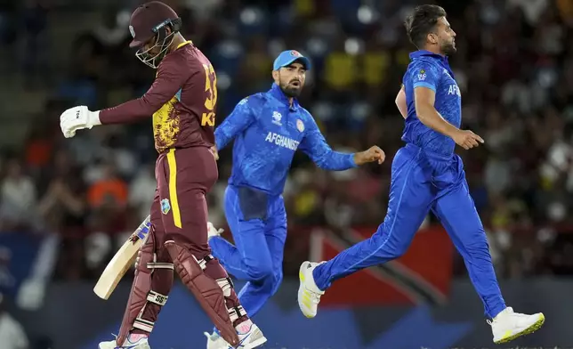 West Indies' batsman Brandon King walks off the field, bolted by Afghanistan's Azmatullah Omarzai, right, during an ICC Men's T20 World Cup cricket match at Daren Sammy National Cricket Stadium in Gros Islet, Saint Lucia, Monday, June 17, 2024. (AP Photo/Ramon Espinosa)