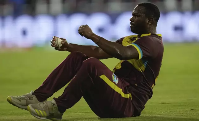West Indies' Johnson Charles hold the ball after taking the catch to dismiss Afghanistan's Najibullah Zadran during an ICC Men's T20 World Cup cricket match at Daren Sammy National Cricket Stadium in Gros Islet, Saint Lucia, Monday, June 17, 2024. (AP Photo/Ramon Espinosa)