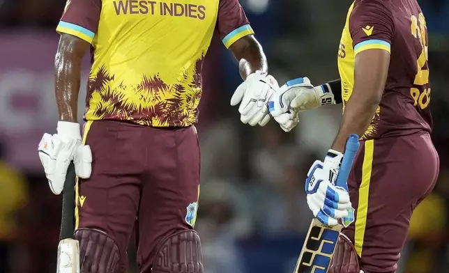 West Indies' batsmen Johnson Charles, left, and Nicholas Pooran bump gloves during their partnership against Afghanistan in an ICC Men's T20 World Cup cricket match at Daren Sammy National Cricket Stadium in Gros Islet, Saint Lucia, Monday, June 17, 2024. (AP Photo/Ramon Espinosa)