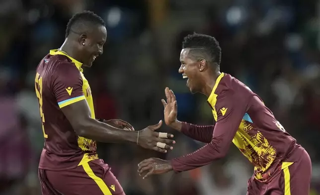 West Indies' captain Rovman Powell, left, celebrates with bowler Akeal Hosein the dismissal of Afghanistan's Karim Janat during an ICC Men's T20 World Cup cricket match at Daren Sammy National Cricket Stadium in Gros Islet, Saint Lucia, Monday, June 17, 2024. (AP Photo/Ramon Espinosa)