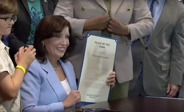 In this still image taken from video of the Office of the New York Governor, Gov. Kathy Hochul displays her signed bill, in New York, Thursday, June 20, 2024. Hochul signed a bill on Thursday that would allow parents to block their children from getting social media posts suggested by a platform's algorithm, a move to limit feeds critics argue are addictive. (Office of the New York Governor via AP)