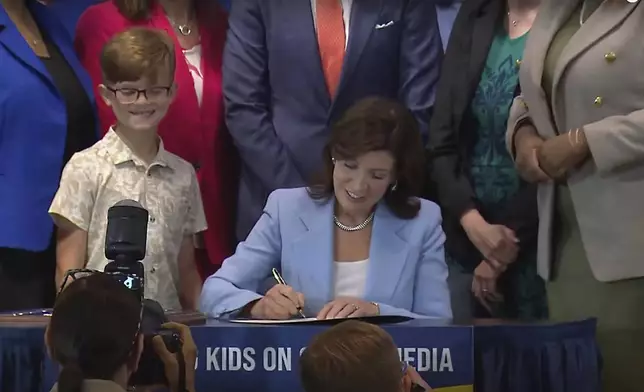 In this still image taken from video of the Office of the New York Governor, Gov. Kathy Hochul signs a bill, in New York, Thursday, June 20, 2024. Hochul signed a bill that would allow parents to block their children from getting social media posts suggested by a platform's algorithm, a move to limit feeds critics argue are addictive. (Office of the New York Governor via AP)