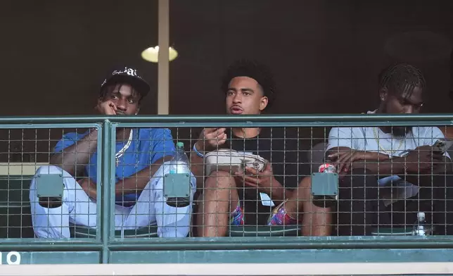 Carolina Panthers wide receiver Terrace Marshall Jr., quarterback Bryce Young and wide receiver Diontae Johnson, from left, watch a baseball game between the Los Angeles Angels and the Detroit Tigers, Thursday, June 27, 2024, in Anaheim, Calif. (AP Photo/Ryan Sun)