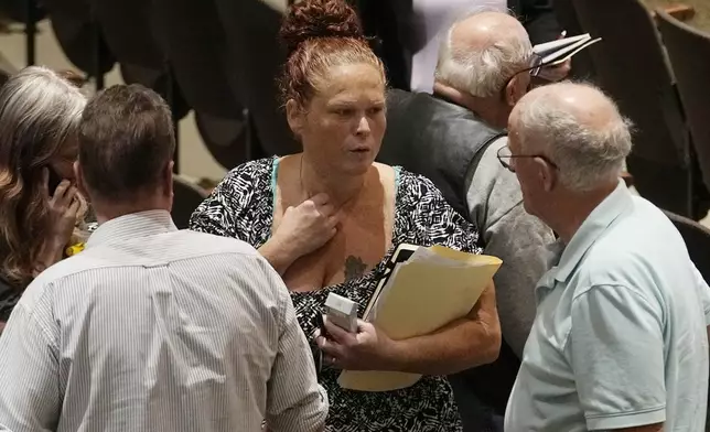 Jami Wallace, center, talks with other audience members during a break in a meeting of the National Transportation Safety Board to discuss and the Norfolk Southern Train Derailment Investigation Tuesday, June 25, 2024, in East Palestine, Ohio. (AP Photo/Sue Ogrocki)