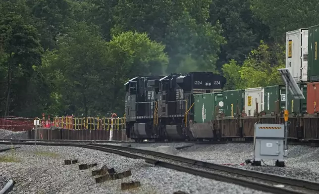 A Norfolk Southern freight train travels through the area where clean-up continues after a train carrying hazardous materials derailed more than a year ago, Tuesday, June 25, 2024, in East Palestine, Ohio. (AP Photo/Sue Ogrocki)