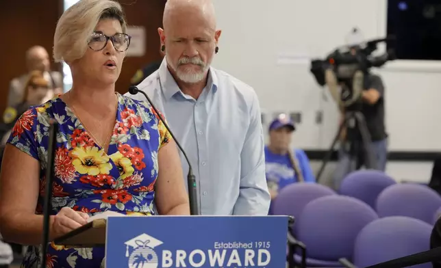Jessica Norton, with her husband, Gary, speaks during the public comment period at a Broward County School Board meeting in Fort Lauderdale held on Tuesday, June 18, 2024. Norton, whose daughter played on the Monarch High School volleyball team, was one of five Monarch officials removed from the school Nov. 27 amid an inquiry into possible violations of the "Fairness in Women's Sports Act," a 2021 law that bans transgender girls from playing on girls' sports teams. Norton is the only one facing potential discipline. (Amy Beth Bennett/South Florida Sun-Sentinel via AP)