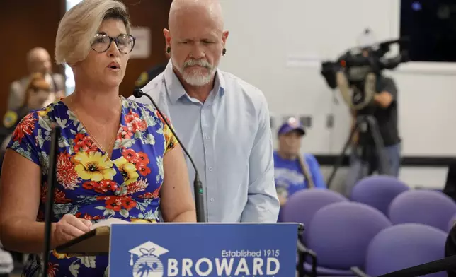 Jessica Norton, with her husband, Gary, speaks during the public comment period at a Broward County School Board meeting in Fort Lauderdale, Fla., Tuesday, June 18, 2024. Norton, whose daughter played on the Monarch High School volleyball team, was one of five Monarch officials removed from the school Nov. 27 amid an inquiry into possible violations of the "Fairness in Women's Sports Act," a 2021 law that bans transgender girls from playing on girls' sports teams. Norton is the only one facing potential discipline. (Amy Beth Bennett/South Florida Sun-Sentinel via AP)
