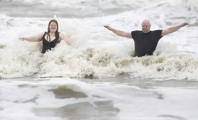 Jeremy Reddout and his daughter, Elexus, enjoy the waves between Murdoch's and Pleasure Pier as rain falls, Wednesday, June 19, 2024, in Galveston, Texas. Tropical Storm Alberto has formed in the southwestern Gulf of Mexico, the first named storm of what is forecast to be a busy hurricane season. (Jason Fochtman/Houston Chronicle via AP)