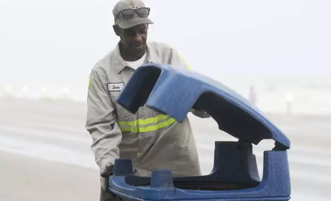 Galveston city worker Sean Kirby checks trash cans along Seawall Boulevard as rain falls Wednesday, June 18, 2024, in Galveston, Texas. Tropical Storm Alberto has formed in the southwestern Gulf of Mexico, the first named storm of what is forecast to be a busy hurricane season. (Jason Fochtman/Houston Chronicle via AP)