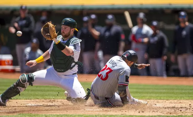 Minnesota Twins Royce Lewis (23) slides into home to score as Oakland Athletics catcher Kyle McCann fields the late throw during the second inning of a baseball game in Oakland, Calif,. Saturday, June 22, 2024. (AP Photo/Nic Coury)