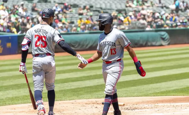 Minnesota Twins' Byron Buxton (25) shakes hands with' Manuel Margot (13) after Margot scored during the first inning of a baseball game against the Oakland Athletics in Oakland, Calif,. Saturday, June 22, 2024. (AP Photo/Nic Coury)