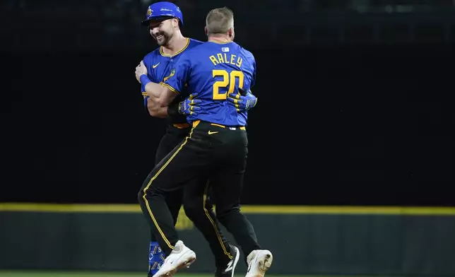 Seattle Mariners' Cal Raleigh, left, is greeted by Luke Raley (20) after hitting a ground ball to drive in the winning run in the 10th inning against the Minnesota Twins in a baseball game Friday, June 28, 2024, in Seattle. The Mariners won 3-2. (AP Photo/Lindsey Wasson)