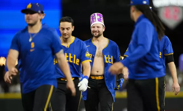 Seattle Mariners' Cal Raleigh wears a gum bucket on his head as he celebrates with teammates after hitting a ground ball to drive in the winning run in the 10th inning against the Minnesota Twins in a baseball game Friday, June 28, 2024, in Seattle. The Mariners won 3-2. (AP Photo/Lindsey Wasson)
