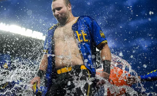 Seattle Mariners' Cal Raleigh is doused by teammates he hit a ground ball to drive in the winning run in the 10th inning against the Minnesota Twins in a baseball game Friday, June 28, 2024, in Seattle. The Mariners won 3-2. (AP Photo/Lindsey Wasson)