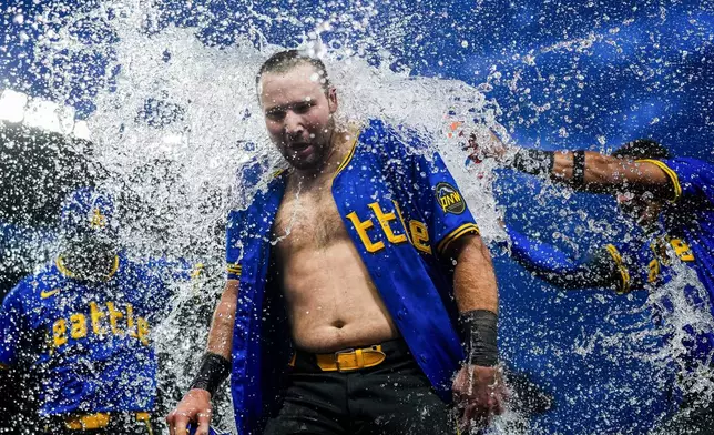 Seattle Mariners' Cal Raleigh is doused by teammates after hitting a ground ball to drive in the winning run in the 10th inning against the Minnesota Twins in a baseball game Friday, June 28, 2024, in Seattle. The Mariners won 3-2. (AP Photo/Lindsey Wasson)