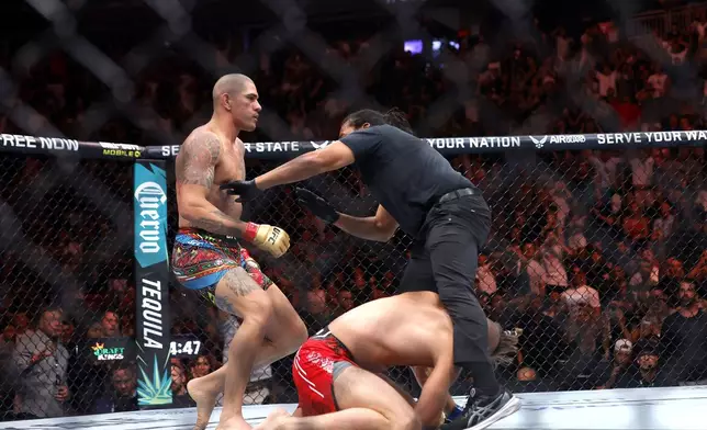 The referee moves in to protect Jiri Prochazka from light heavyweight champion Alex Pereira, left, during the UFC 303 mixed martial arts event Saturday, June 29, 2024, in Las Vegas. Pereira retained his title. (Steve Marcus/Las Vegas Sun via AP)