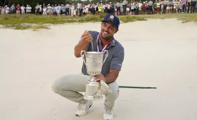 Bryson DeChambeau holds the trophy in the bunker after winning the U.S. Open golf tournament Sunday, June 16, 2024, in Pinehurst, N.C. (AP Photo/Matt York)