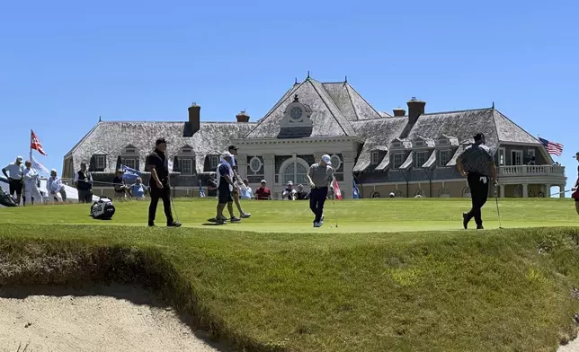 Frank Bensel, center, plays on the 18th green in front of the Newport Country Club clubhouse during the second round of the U.S. Senior Open golf tournament in Newport, R.I., Friday, June 28, 2024. Bensel turned up a pair of aces back-to-back holes. (AP Photo/Chris Lehourites)
