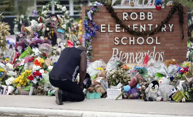 FILE - Reggie Daniels pays his respects a memorial at Robb Elementary School, June 9, 2022, in Uvalde, Texas, created to honor the victims killed in the school shooting. The former Uvalde schools police chief and another former officer have been indicted over their role in the slow police response to the 2022 massacre in a Texas elementary school that left 19 children and two teachers dead, according to multiple reports Thursday, June 27, 2024. (AP Photo/Eric Gay, File)