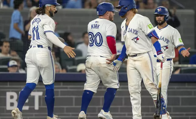 Toronto Blue Jays' Justin Turner congratulates teammates Bo Bichette (11), Alejandro Kirk (30) and Isiah Kiner-Falefa (right) after the three scored on a Vladimir Guerrero Jr. double in the sixth inning of a baseball game against the New York Yankees, Saturday, June 29, 2024, in Toronto. (Frank Gunn/The Canadian Press via AP)