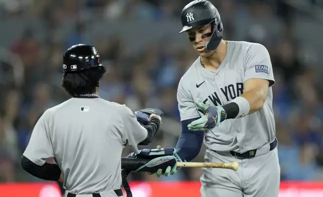 New York Yankees' Aaron Judge (99) hands off his gear to a batboy after an intentional walk during the third inning of a baseball game against the Toronto Blue Jays in Toronto, Saturday, June 29, 2024. (Frank Gunn/The Canadian Press via AP)