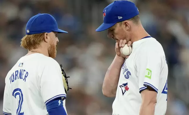 Toronto Blue Jays pitcher Chris Bassitt (40) shows a mark he got from being hit by a line drive to teammate Justin Turner (2) during the first inning of a baseball game against the New York Yankees in Toronto, Saturday, June 29, 2024. (Frank Gunn/The Canadian Press via AP)